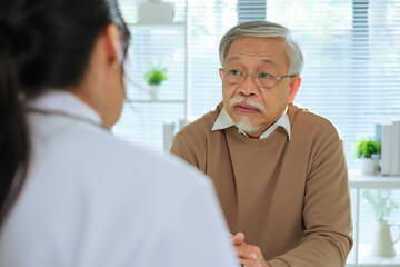 Obraz premium Doctor Reviewing Medical File While Interviewing Elderly Patient at Clinic or Hospital