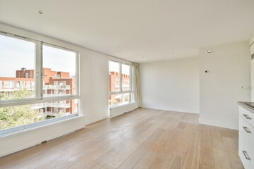 An airy, uncluttered space with large windows allowing ample natural light, showcasing a minimalist design and wooden flooring for a contemporary feel.