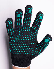 Black safety work glove with green rubber grip dots on white background