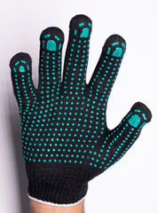 Black safety work glove with green rubber grip dots on white background
