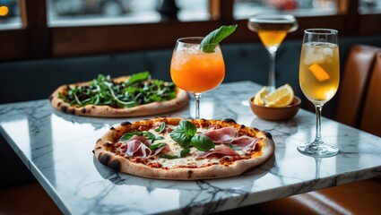 Table decor in a cafe restaurant, displaying two pizzas with burnt edges alongside cold summer cocktails on a marble square table.