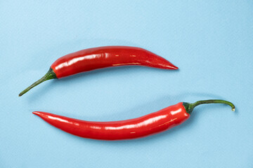 Sharp and Spicy Two Red Chilies Top View on Blue Background
