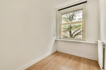 A spacious, well-lit room featuring a large window that invites natural light. The simple decor emphasizes minimalism and tranquility.