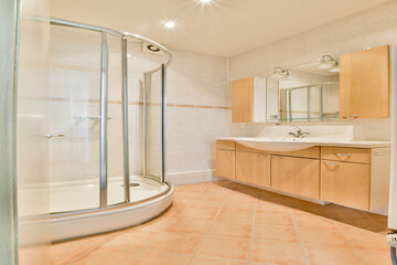 A stylish bathroom featuring a glass shower, wooden cabinets, and modern fixtures. The design...