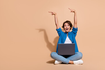 Full length size photo of amazed woman sitting with macbook pro pointing fingers novelty apple...
