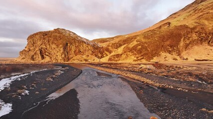 Iceland's Skógá River meanders through a dramatic landscape near Skógafoss waterfall. Moody sky over volcanic terrain. Perfect for travel, nature, or adventure themes.