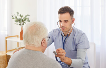 Obraz premium Confident doctor or caregiver uses a stethoscope to listen to the lungs and breathing of a senior man, a patient in a hospital. Healthcare, patient care, and respiratory examination.