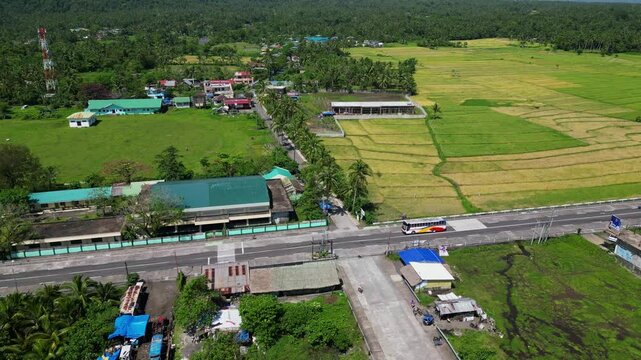 Aerial overview of provincial highway going through four-way intersection at Daraga Legazpi Tiwi Road, Albay, Philippines surrounded by lush greenery.