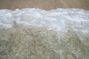 Soft wave of the sea on the sandy beach. Close-up.