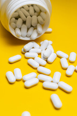 White Pills Spilling from Bottle on Bright Yellow Background