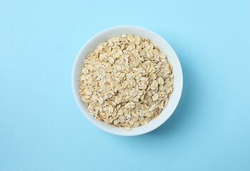 Composition with oatmeal flakes on blue background. Cooking breakfastб top view