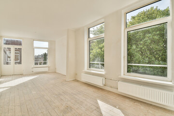Fototapeta premium Spacious room with large windows allowing natural light, featuring minimalist decor and light-colored walls, creating an inviting atmosphere.