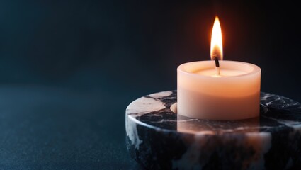 Detailed view of a lit candle emitting a warm glow amidst darkness, suggesting calm and serenity.