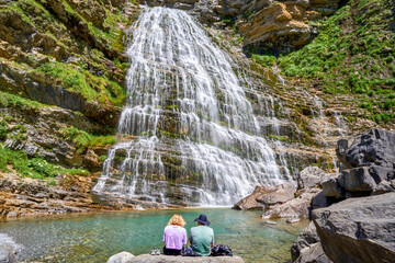 Couple in the Ordesa Valley contemplating the spectacular Cola de Caballo waterfall, Pyrenees, Spain.