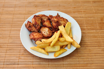 A plate of fried chicken and french fries. The chicken is cut into pieces and the fries are golden brown