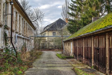 Abandoned courtyard buildings with weathered facades and overgrown garages