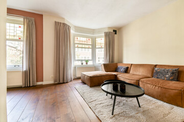 Fototapeta premium A bright and inviting living room featuring large windows, soft curtains, and comfortable seating that embodies a warm ambiance for relaxation.