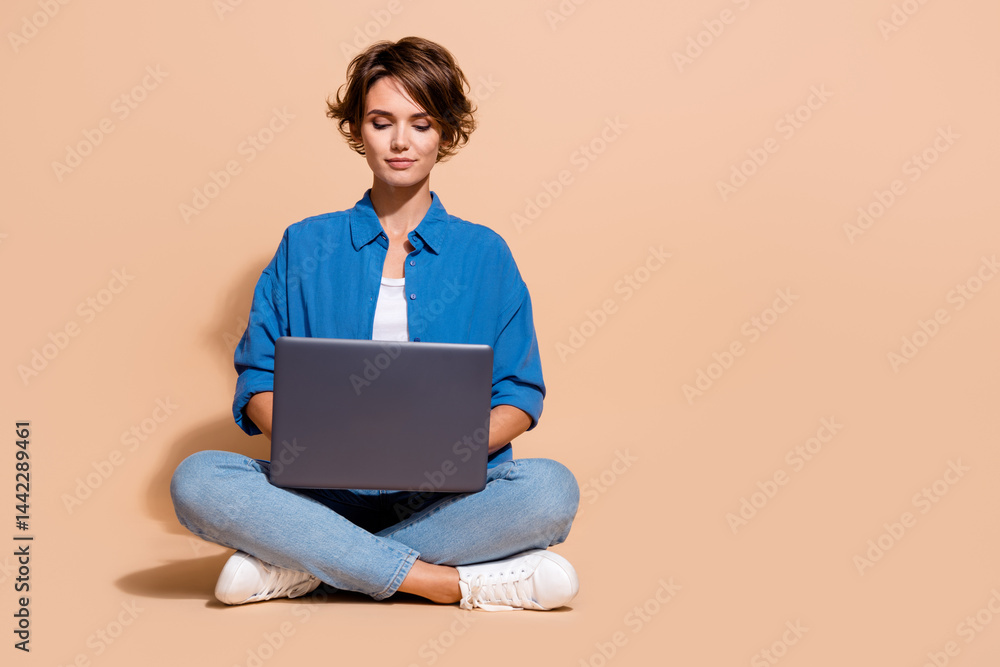 Poster Photo of freelancer specialist lady sitting with netbook coding for distant project on upwork market isolated over beige color background