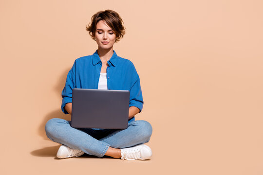 Photo of freelancer specialist lady sitting with netbook coding for distant project on upwork market isolated over beige color background
