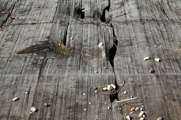Cracked rooftop surface with scattered debris and visible damage from wear and exposure