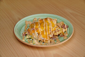 A plate of food with a green plate and a yellow sauce. The food is a sandwich with cheese and bacon