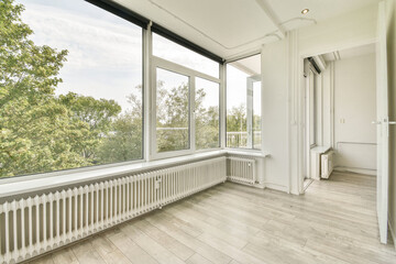 Fototapeta premium Spacious room featuring large windows that allow natural light to flood in, highlighting the beautiful wooden flooring and minimalistic design.