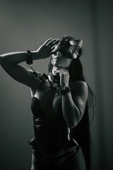 Sensual woman in cat mask and handcuffs striking a pose under neon lights at night