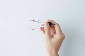 Stationery compass in the hand of a Caucasian woman. White background.
