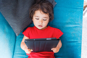 Baby toddler girl watching alone a tablet, screen time and screen addiction in children. Concept of children and technology and screen time