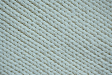 white texture of knitted wool fabric as a background, white smooth symmetrical lines of hand-knitted needlework pattern	
