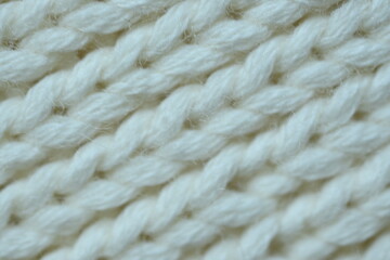white texture of knitted wool fabric as a background, white smooth symmetrical lines of hand-knitted needlework pattern	
