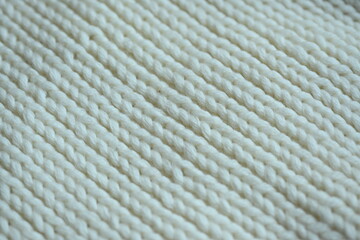white texture of knitted wool fabric as a background, white smooth symmetrical lines of hand-knitted needlework pattern	
