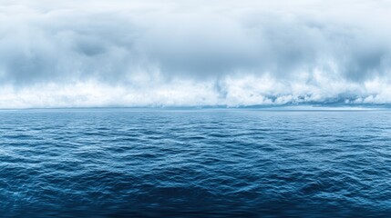 A vast, deep blue ocean with small waves, set against a cloudy sky.
