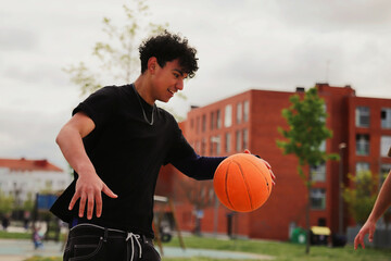 Fototapeta premium Teenagers playing street basketball, competition and friendship concept