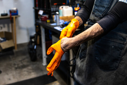 Bike mechanic wearing orange gloves in workshop