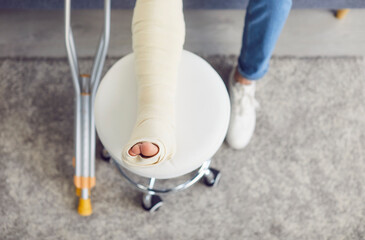 Broken bandaged leg foot injury close up, crutches, patient on rehabilitation, painful trauma...