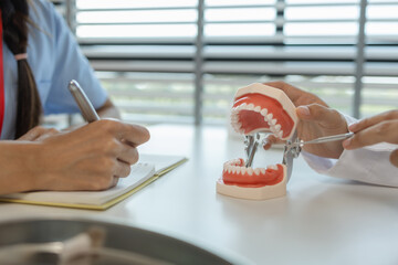the dentist is explaining to the assistant how she will treat a patient with wisdom teeth, the two...