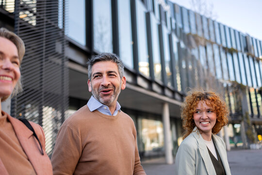 Colleagues walking and conversing happily outside an office building