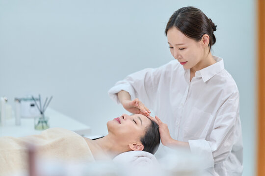 Female Spa Therapist Giving Head Massage to Woman in Wellness Center