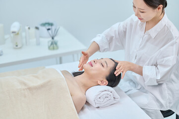 Obraz premium Female Spa Therapist Giving Head Massage to Woman in Wellness Center