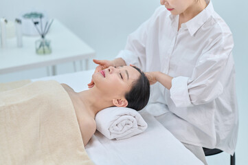 Obraz premium Female Spa Therapist Giving Head Massage to Woman in Wellness Center