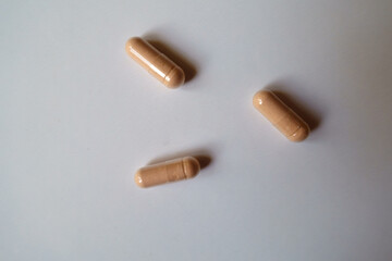 Three pink capsules of palmitoylethanolamide dietary supplement