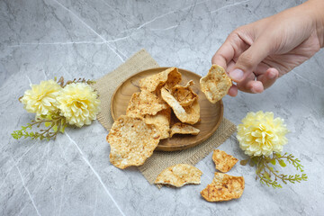 Traditional Sweet Cassava Chips (Opak) in Wooden Plate with Hand and Floral Decor