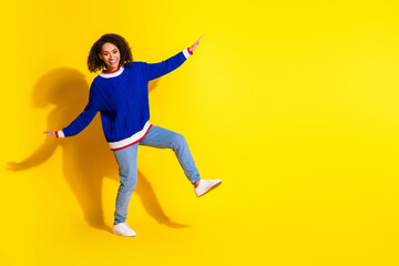 Fototapeta na wymiar Cheerful young woman in casual clothes posing against a vibrant yellow background in a fun and playful manner