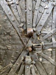 Fragment of ancient wooden door covered sheets of iron with forged metal rusty strips, fixed with...