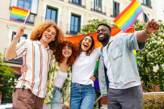 Happy multi ethnic friends celebrating lgbt pride month waving rainbow flags