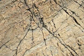 Closeup of grey-brown rock surface with cracks