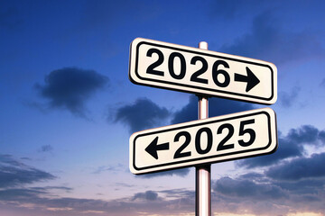 Road signs indicate the path to the new year 2026 and the old year 2025 on a blue sky, creative...