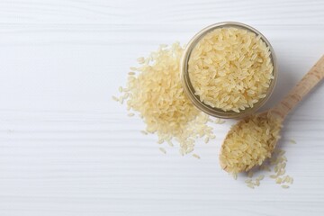 Raw brown rice in wooden spoon and in a jar on white background