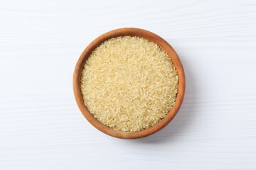 Raw brown rice in a bowl on white background